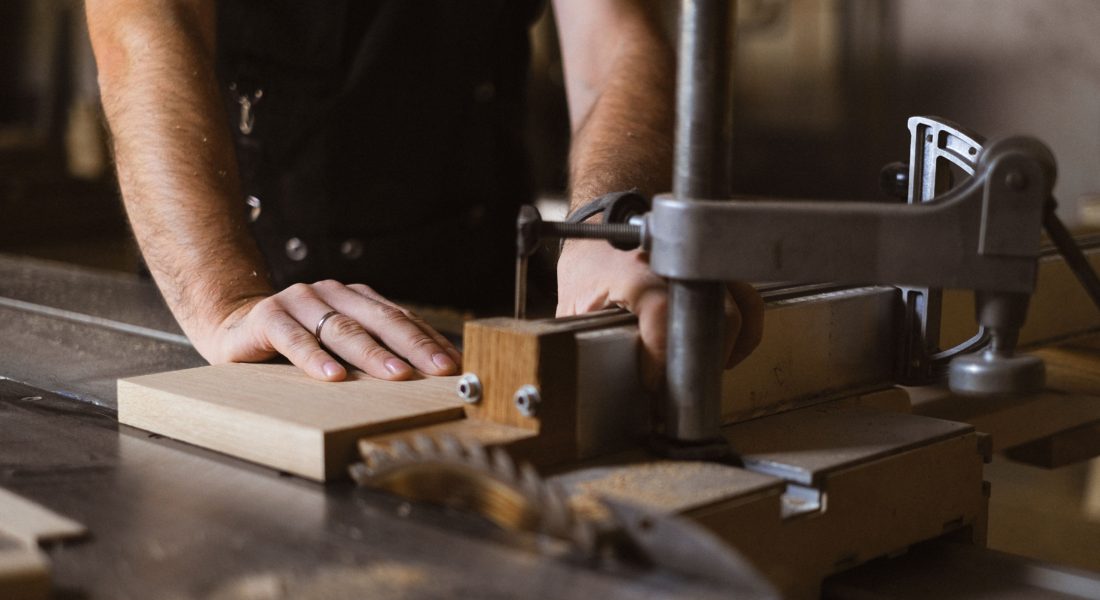 A man cutting a piece of wood with a saw