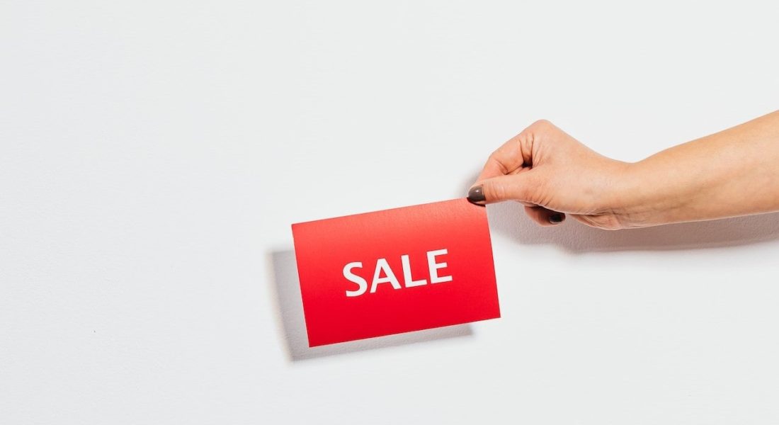 A finger holding a Sale Sign